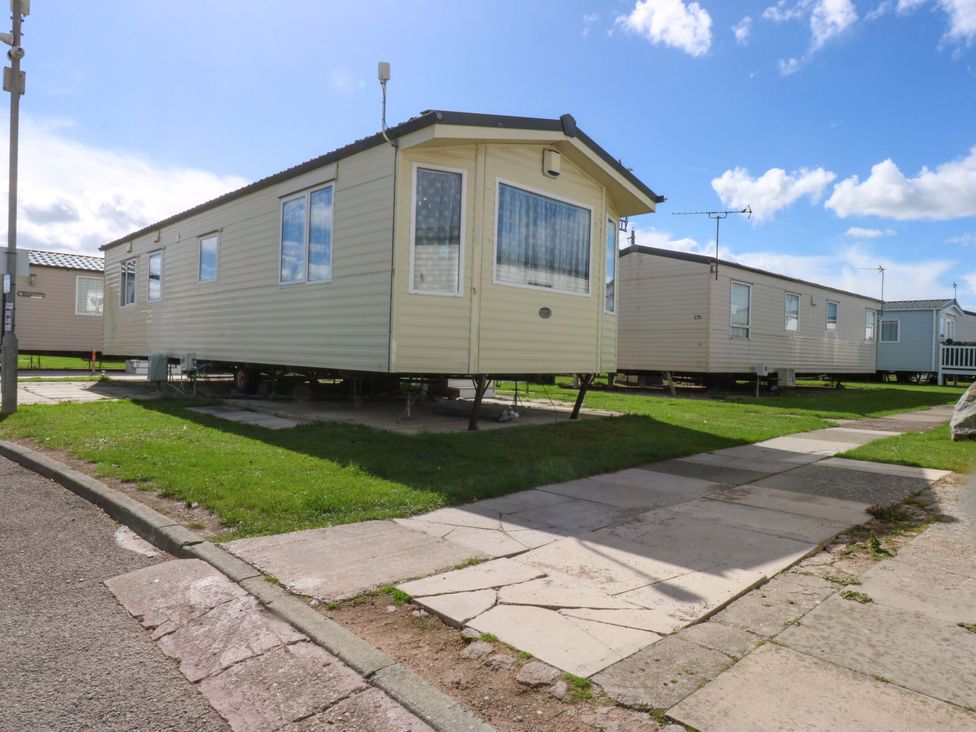 A static caravan on a path with grass at Hideaway Lodge in Abergele