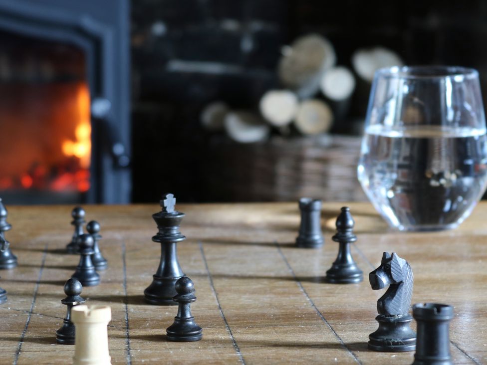 A chess set and a glass of water in a living room with a fireplace at The Old Post Box 