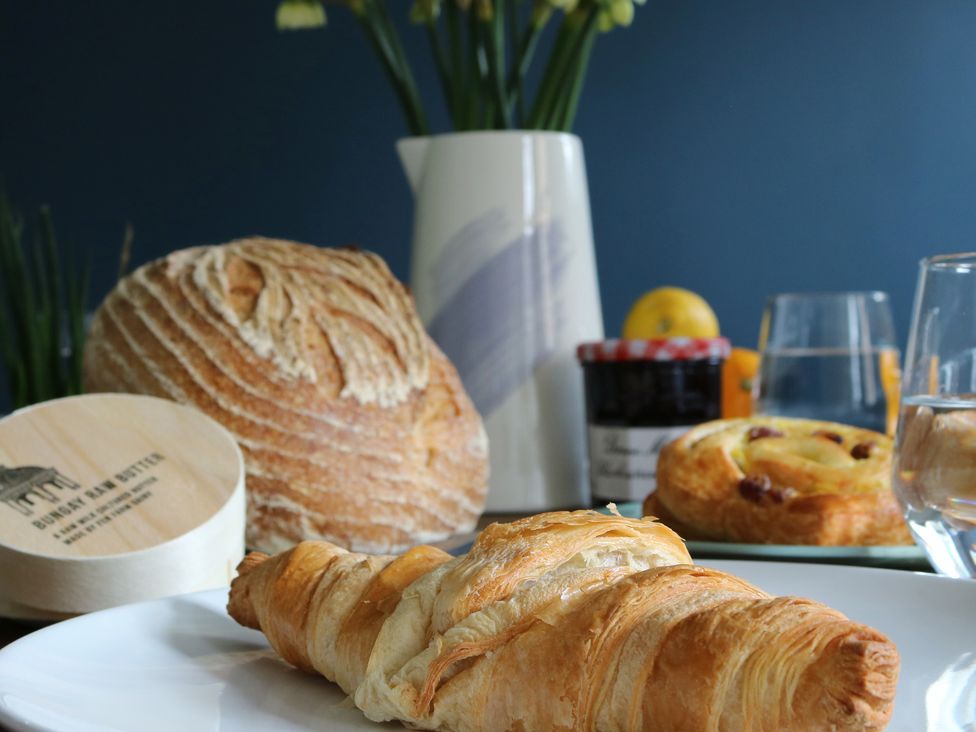A kitchen table with bread, butter, croissant, jam, and a vase at The Old Post Box 