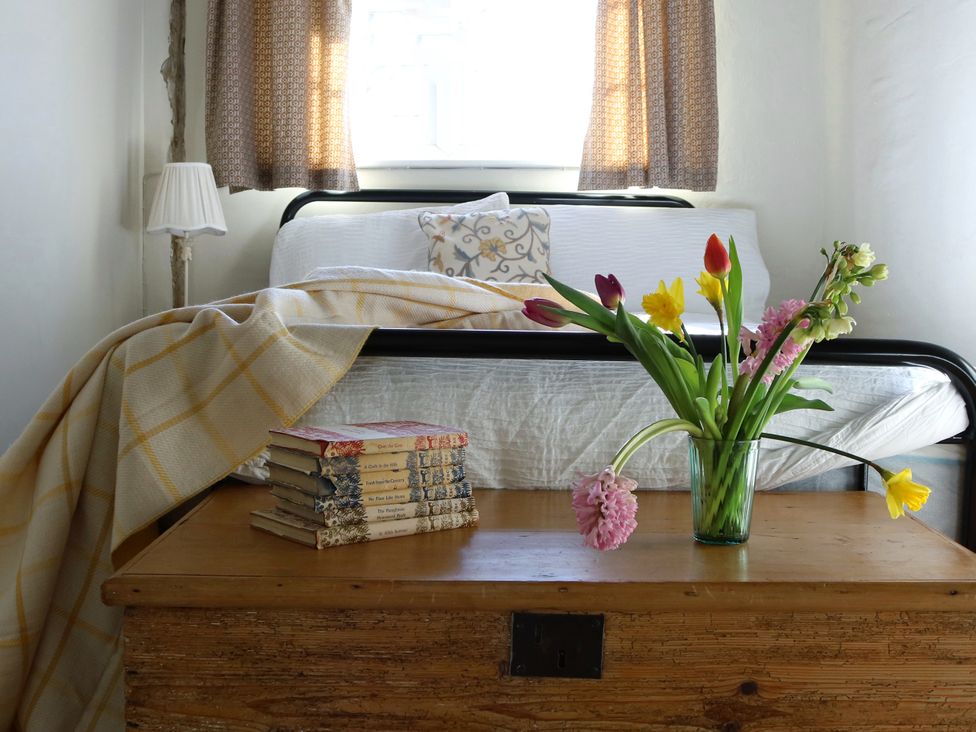 A bedroom with a bed, lamp, and flowers on a table at The Old Post Box