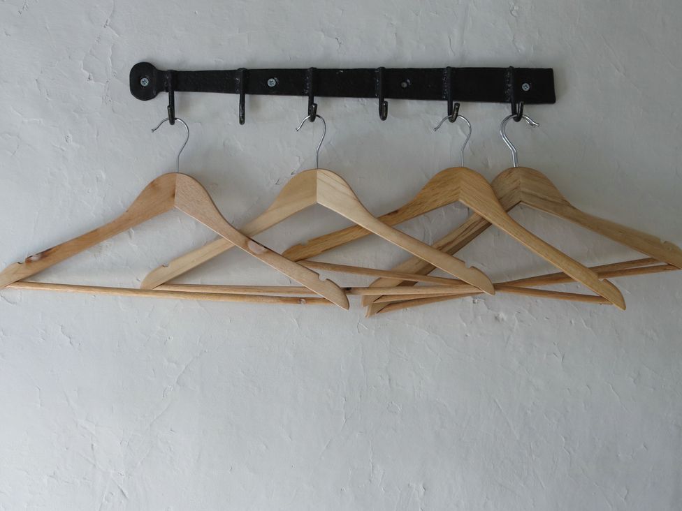 Hangers on a wall-mounted rack in a clothing storage area at The Old Post Box