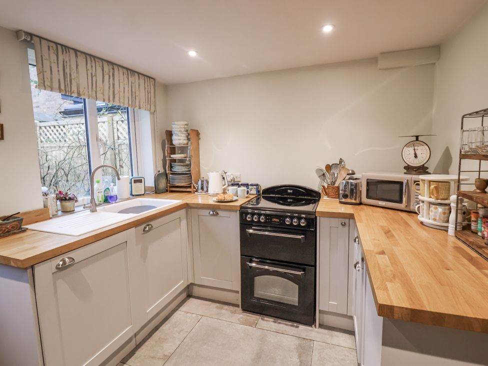 A kitchen with a stove, microwave, and sink at The Old Post Box in Halesworth