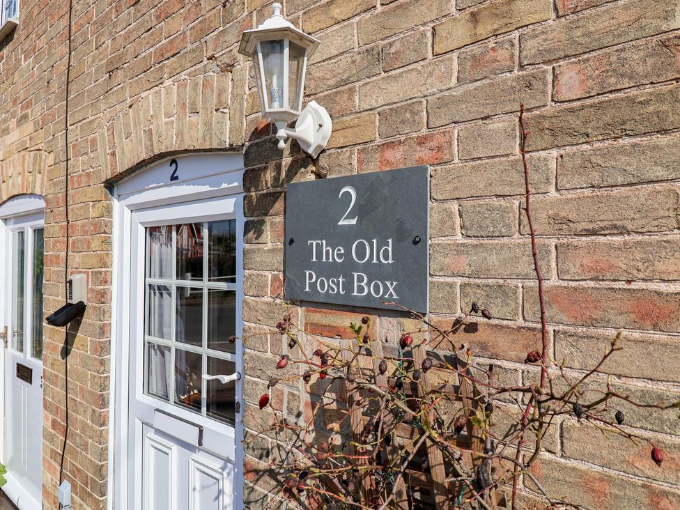 A house number and sign on a wall at The Old Post Box in Halesworth