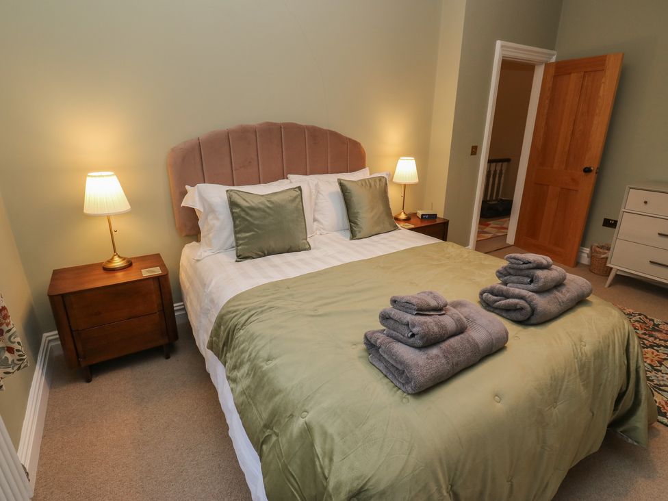 A bedroom with a bed made and towels arranged at Fairfield House in Almondbury