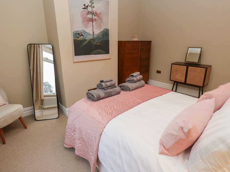 A bedroom with a bed, towels on the bed, and a mirror at Fairfield House in Almondbury