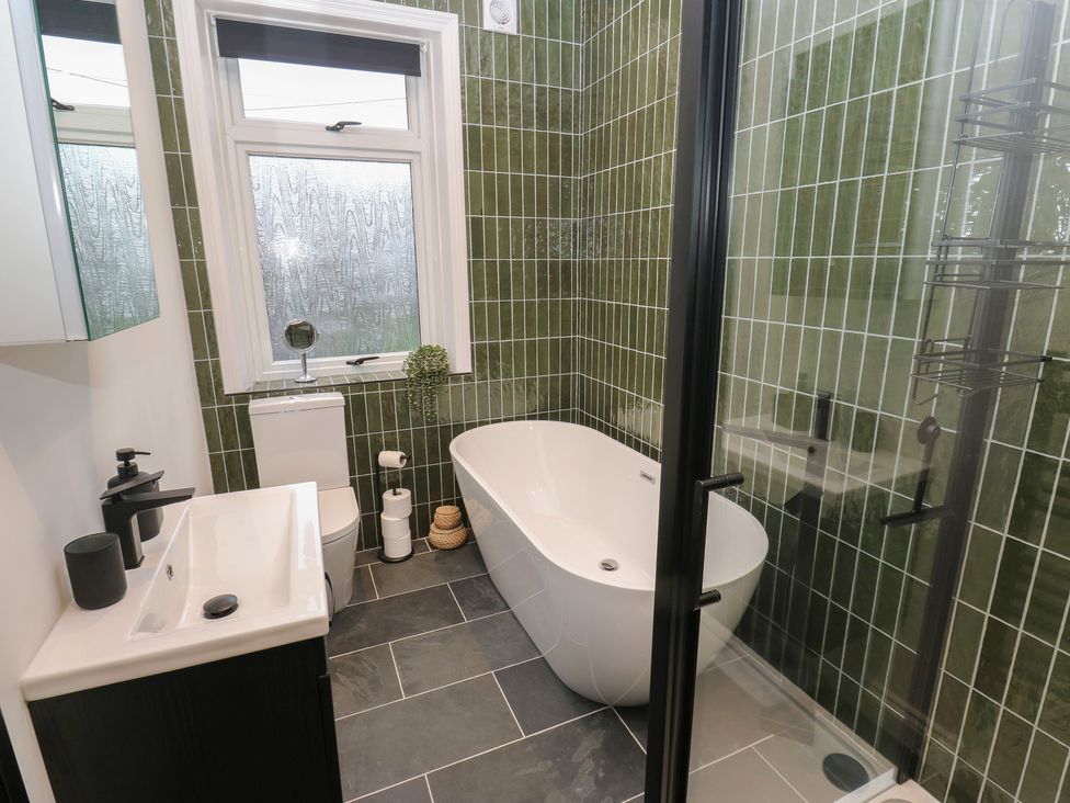 A bathroom with bathtub, shower, toilet, and sink at Fairfield House Almondbury