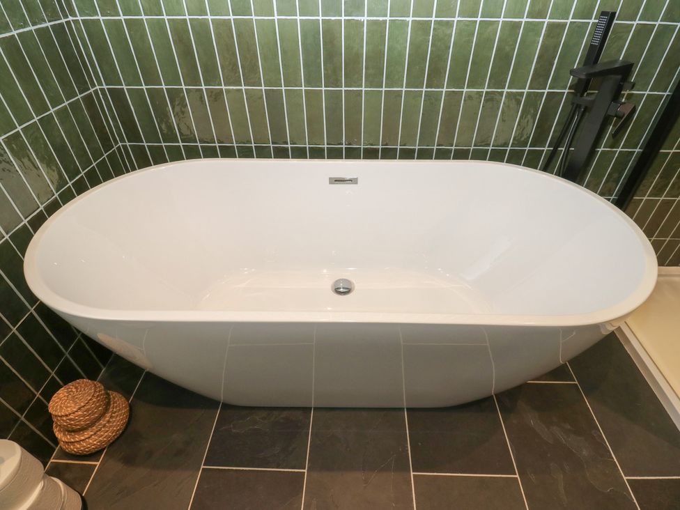 A bathtub in a bathroom with tiled walls at Fairfield House in Almondbury
