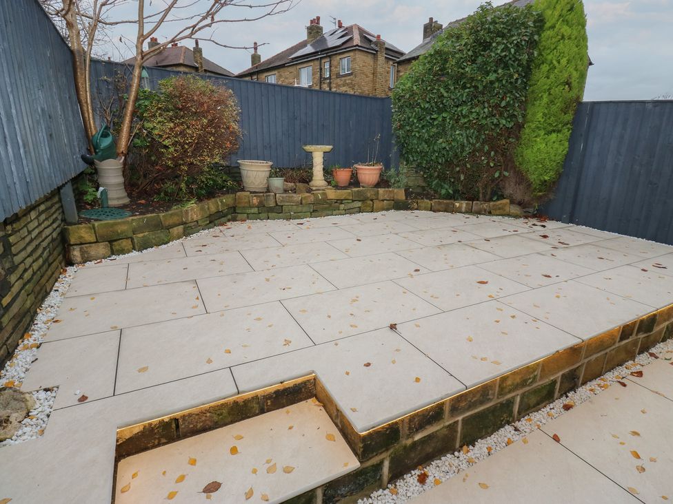 A garden with patio tiles and flower pots at Fairfield House Almondbury