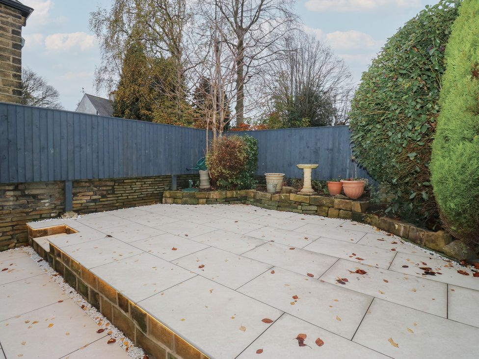 A garden with a paved area and planters at Fairfield House Almondbury