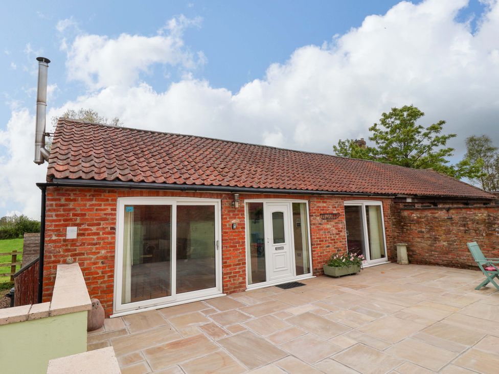 An exterior view of a brick building with a patio at The Owl Barn Cottage
