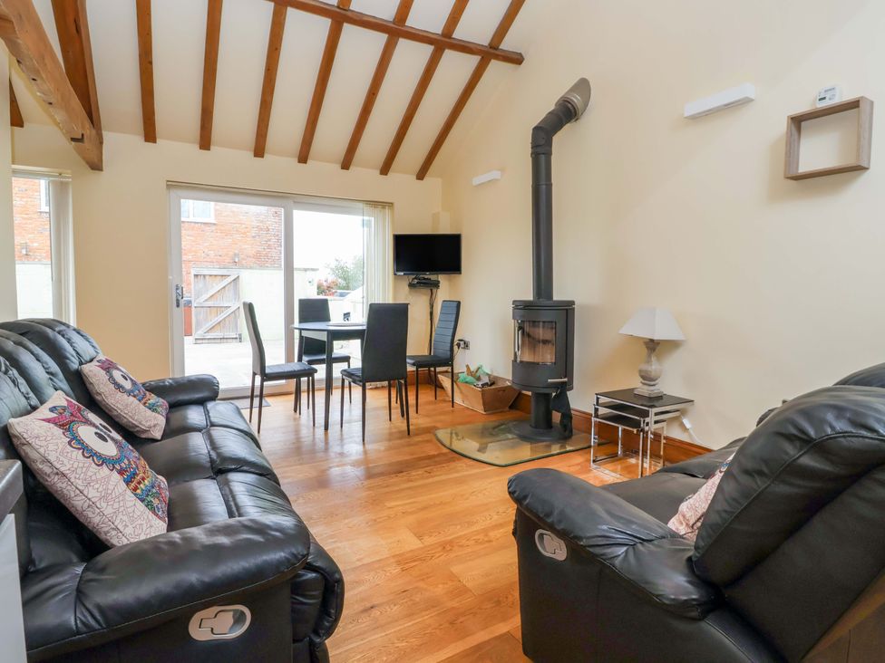 A living room with a sofa and dining area at The Owl Barn Cottage