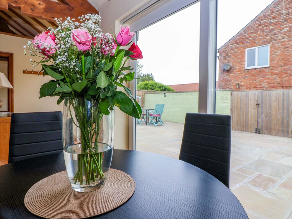 A dining room with a vase of flowers on a table at The Owl Barn Cottage