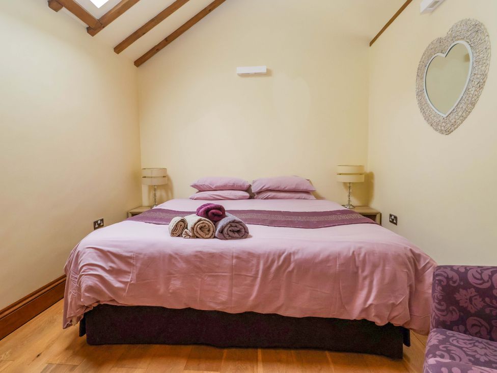A bedroom with a bed and seating area at The Owl Barn Cottage 