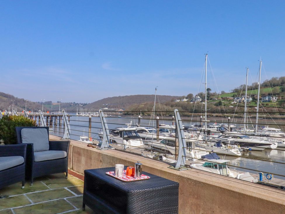 An outdoor area with chairs and a table overlooking a marina at 26 Dart Marina