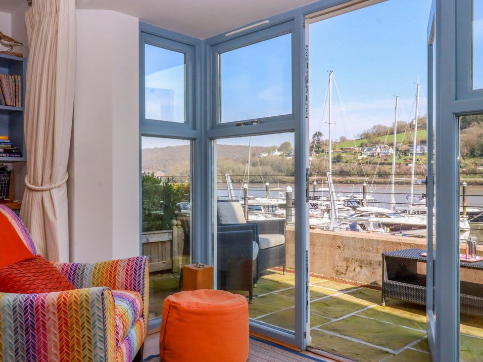 A living room with an armchair and view of boats at 26 Dart Marina