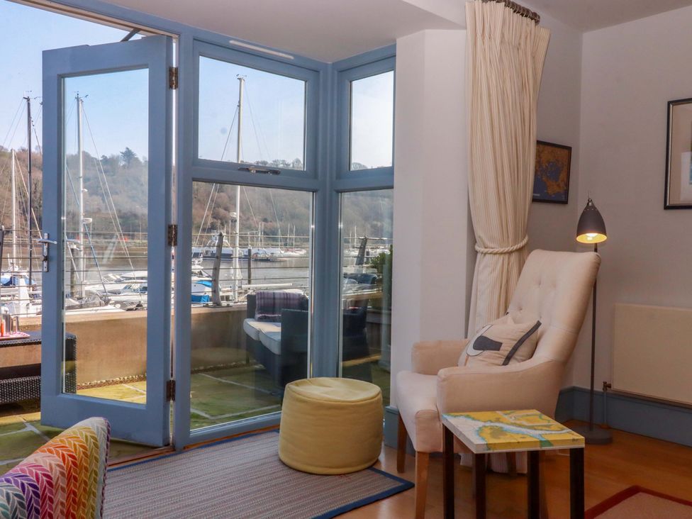 A living room with an armchair and door opening to a marina view at 26 Dart Marina 