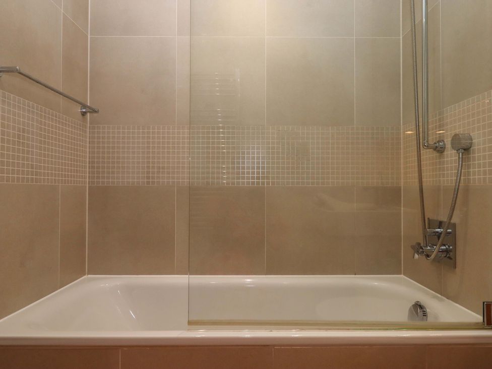 A bathroom with a bathtub and shower facilities at 26 Dart Marina