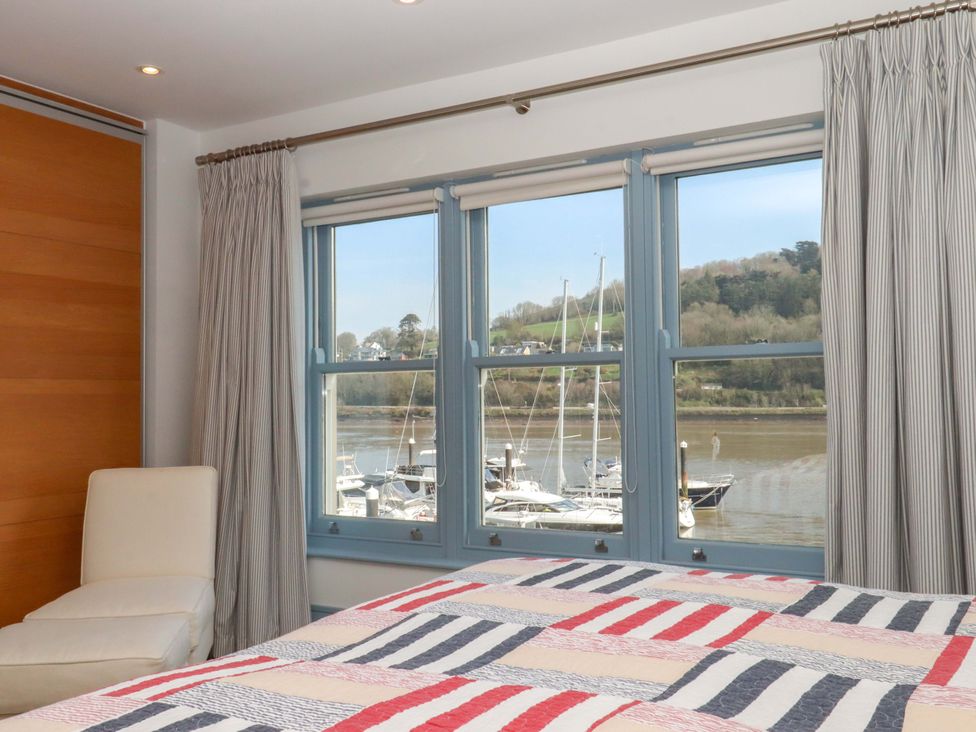A bedroom with windows overlooking a marina at 26 Dart Marina