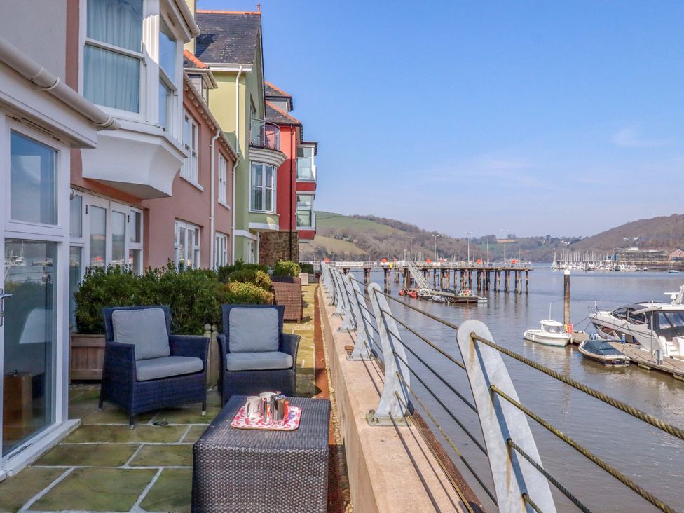 An outdoor seating area with chairs and table by the river at 26 Dart Marina
