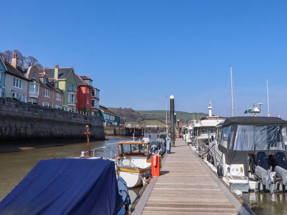 A dock with boats and houses along the waterfront at 26 Dart Marina