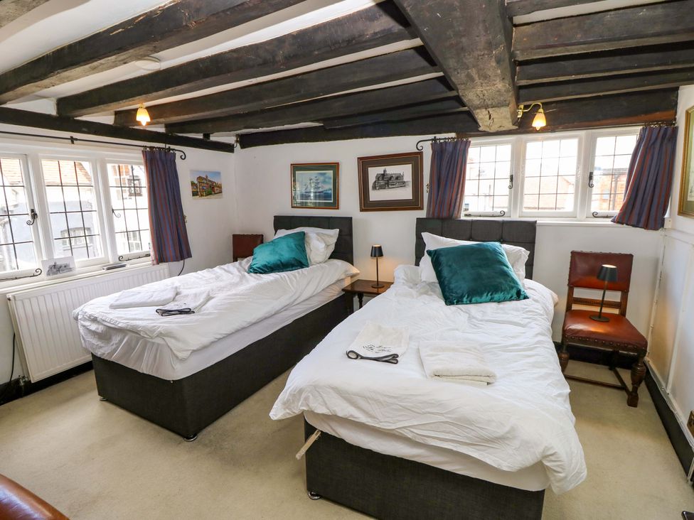 A bedroom with two beds and pictures on the wall at The Old House in Hamble