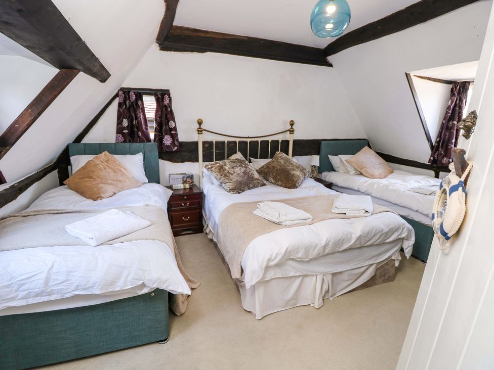 A bedroom with three beds and a bedside table at The Old House in Hamble