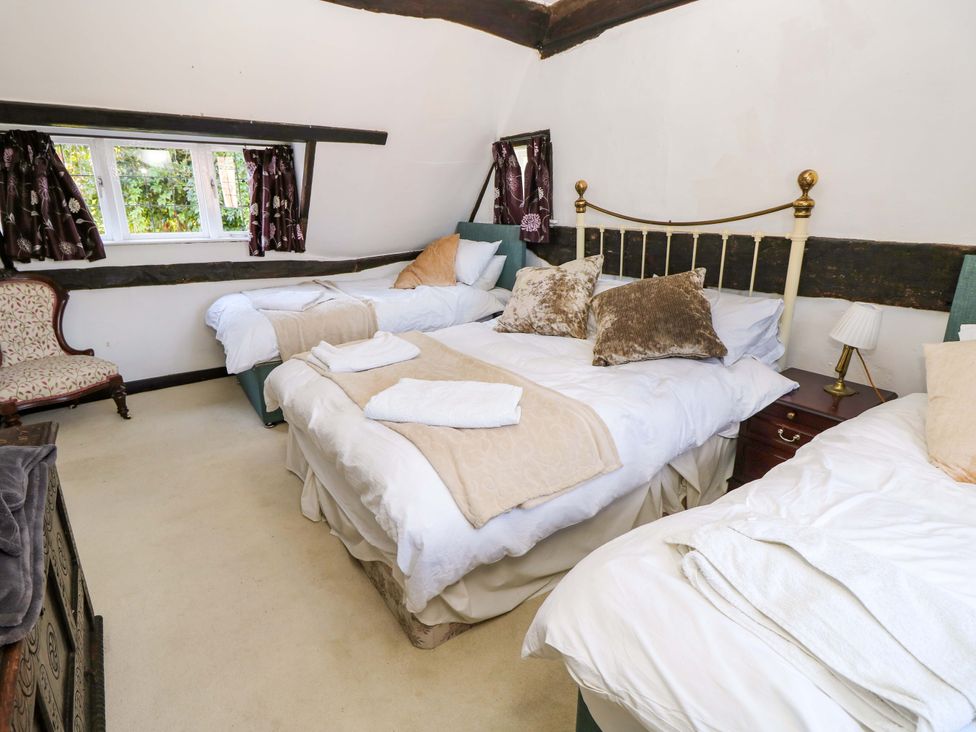 A bedroom with three beds and a chair at The Old House in Hamble