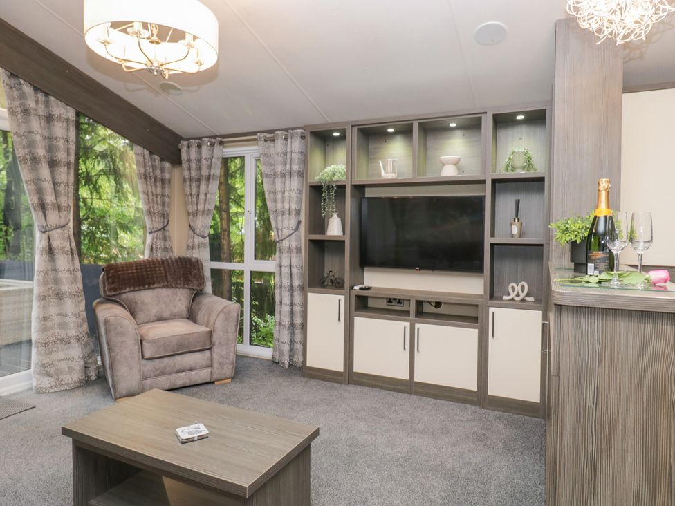 A living room with a chair and television at Feather Hill Lodge in Windermere