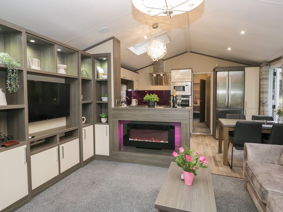 A living room with a fireplace and dining area at Feather Hill Lodge, Windermere