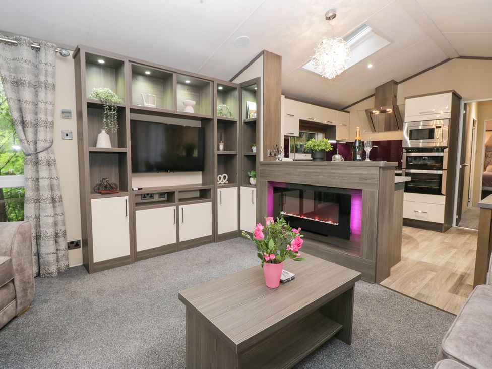 A living room with a television and fireplace at Feather Hill Lodge in Windermere