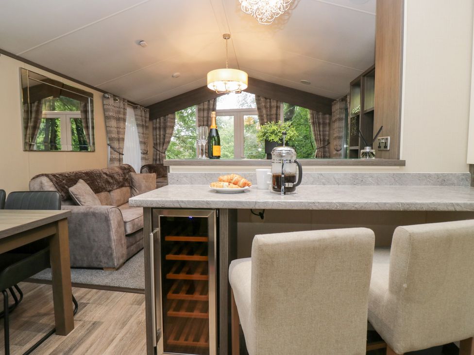 A living room with a sofa and dining area at Feather Hill Lodge in Windermere