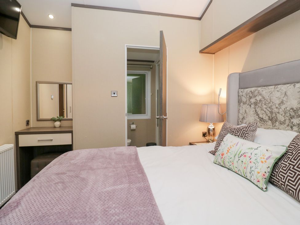 A bedroom with a bed and a mirror at Feather Hill Lodge in Windermere