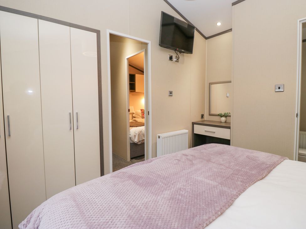 A bedroom with a wardrobe and a television at Feather Hill Lodge in Windermere