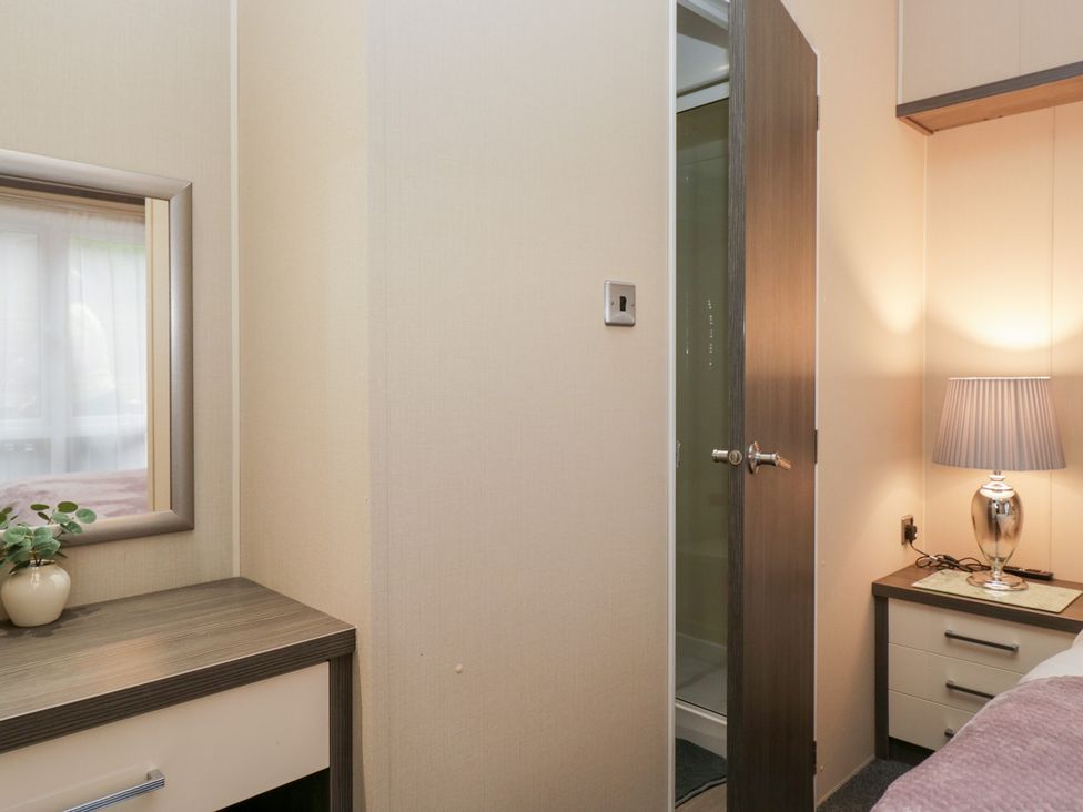 A bedroom with a mirror and a lamp at Feather Hill Lodge in Windermere