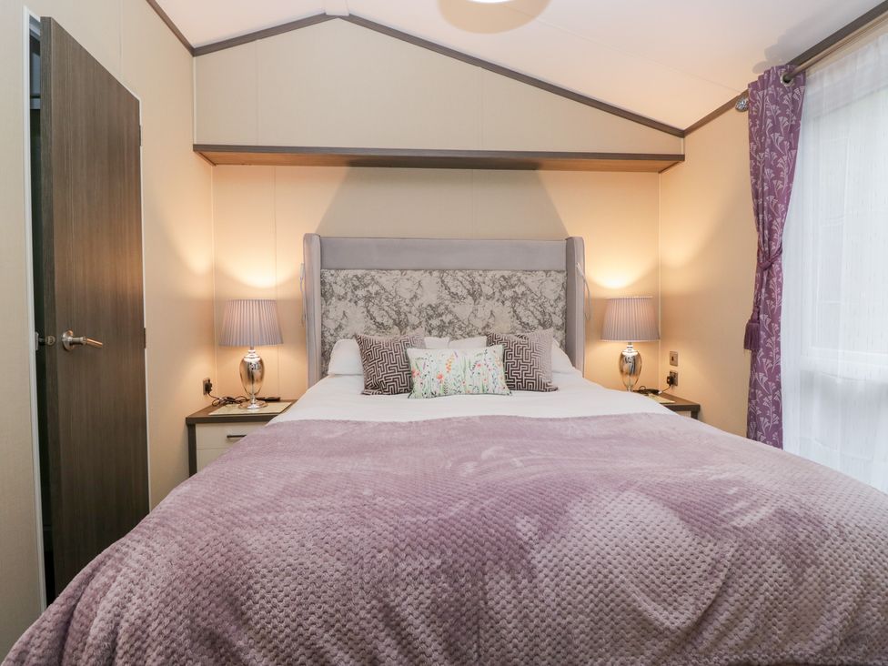 A bedroom with a large bed and bedside lamps at Feather Hill Lodge in Windermere