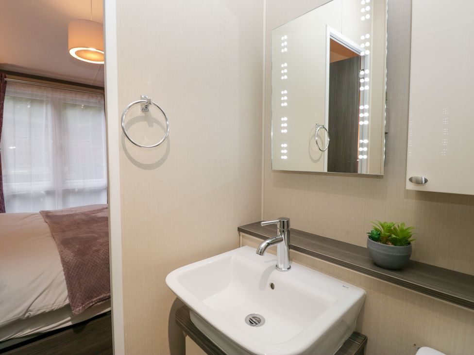 A bathroom with a sink and mirror at Feather Hill Lodge in Windermere