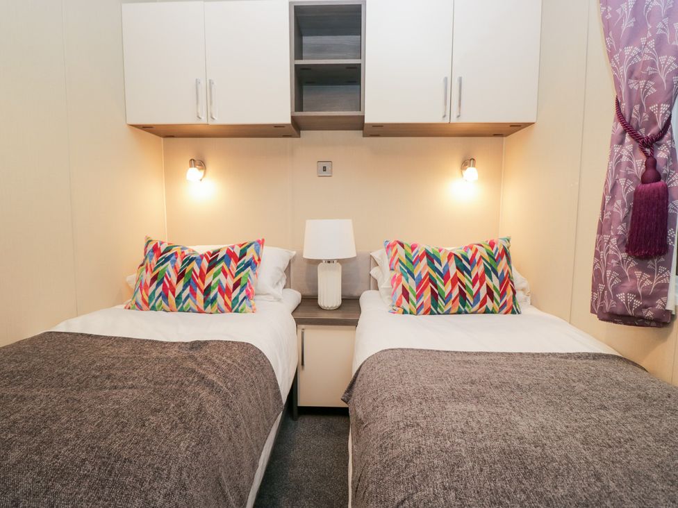 A bedroom with two single beds and a lamp at Feather Hill Lodge in Windermere