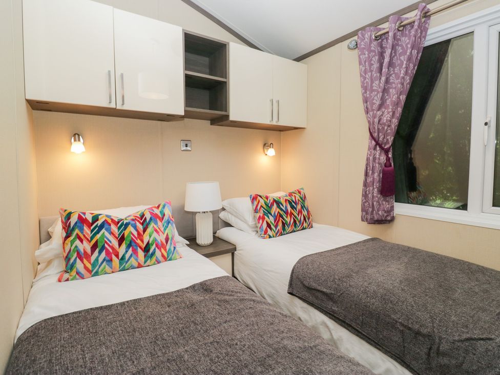 A bedroom with twin beds and decorative pillows at Feather Hill Lodge in Windermere