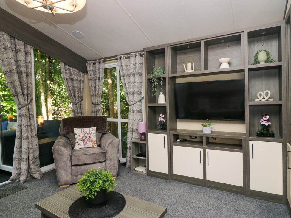 A living room with television and armchair at Feather Hill Lodge White Cross Bay, Skiptory Howe 38 near Troutbeck Bridge
