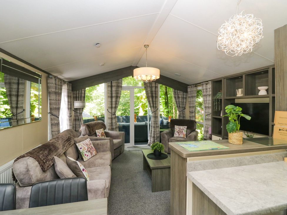 A living room with sofas, a coffee table, and a television stand at Feather Hill Lodge White Cross Bay near Troutbeck Bridge