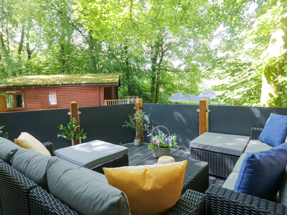 An outdoor seating area with a sofa and table near a cabin at Feather Hill Lodge White Cross Bay, Skiptory Howe 38 White Cross Bay near Troutbeck Bridge