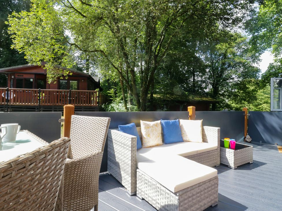 An outdoor patio with seating and a log cabin in the background at Feather Hill Lodge White Cross Bay, Skiptory Howe 38 near Troutbeck Bridge