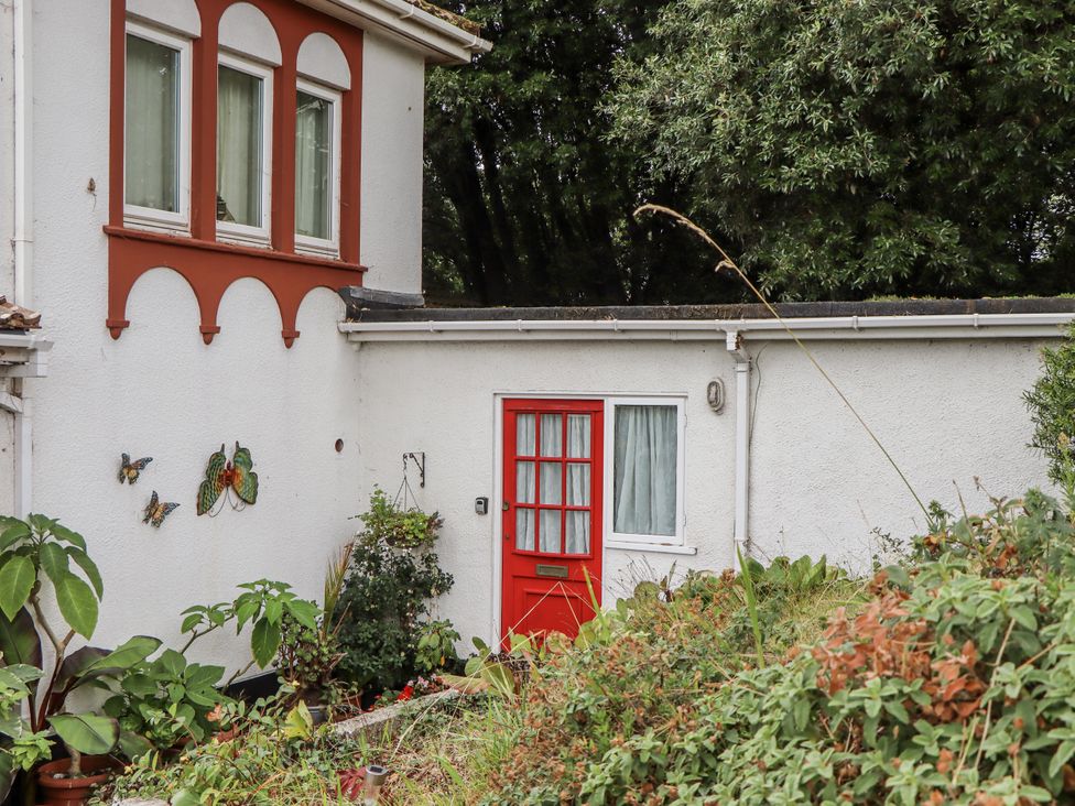 An outdoor area with a red door and decorative butterflies at Mayflower View in Dawlish