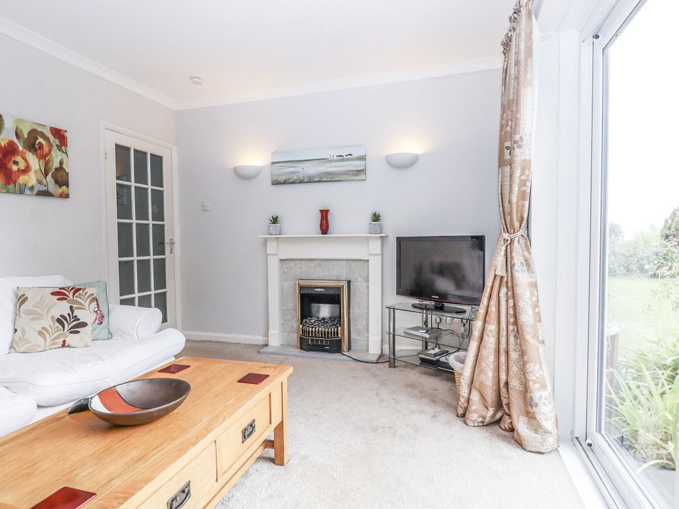 A living room with a sofa, coffee table, and television at Mayflower View in Dawlish