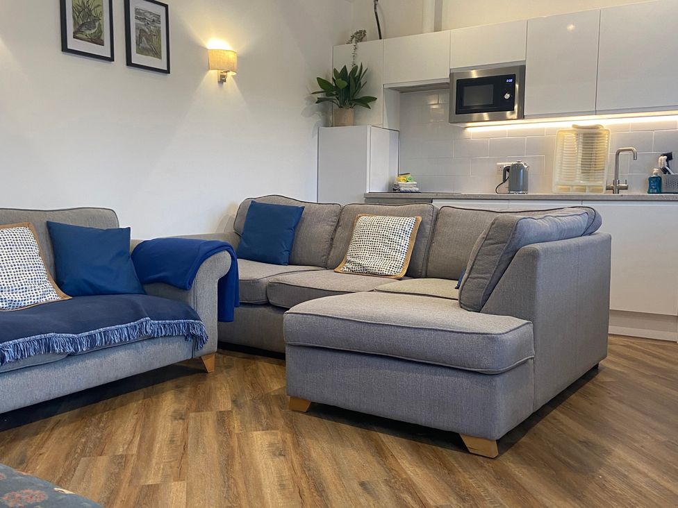 A living room with a sofa and kitchenette at The Cart Shed in Bedford
