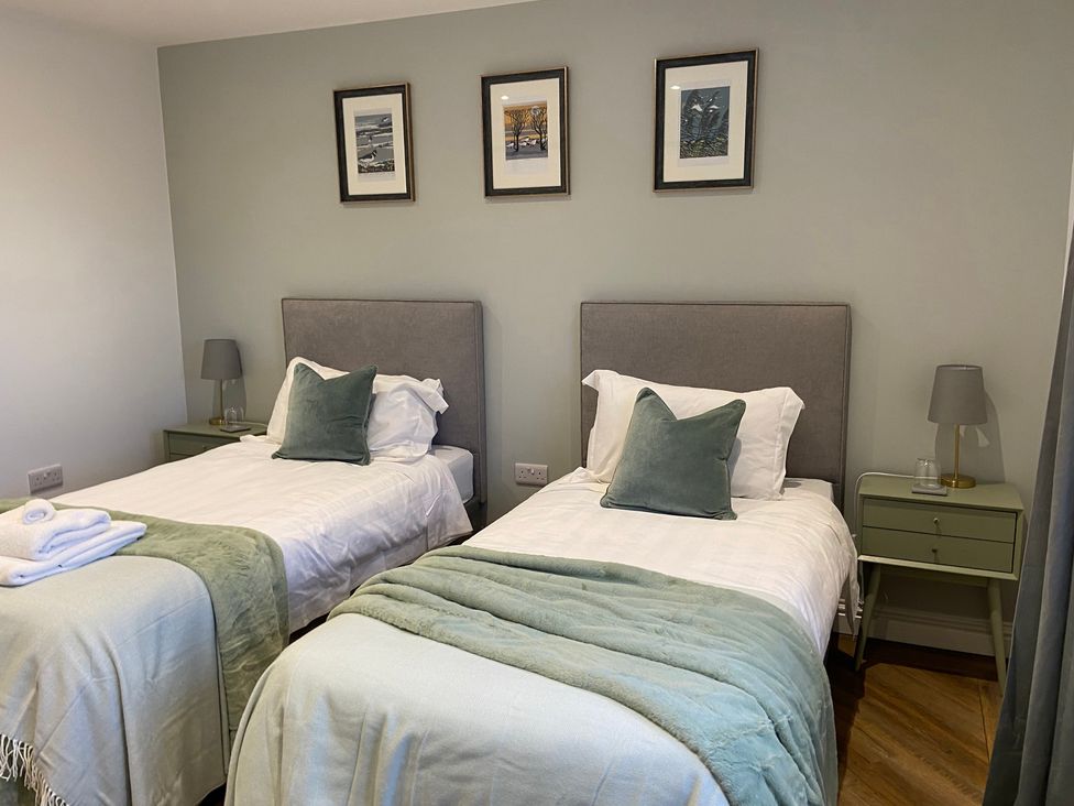 A bedroom with twin beds and bedside table at The Cart Shed in Bedford
