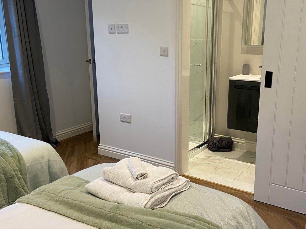 A bathroom with a shower, sink, and towels at The Cart Shed in Bedford