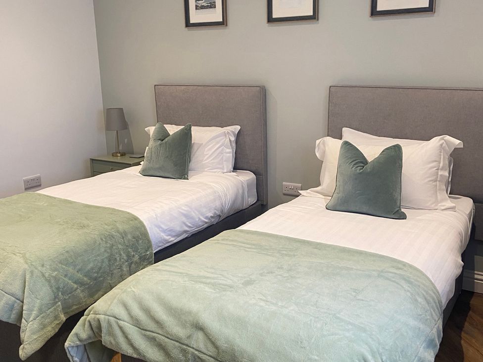 A bedroom with twin beds and bedside lamp at The Cart Shed in Bedford