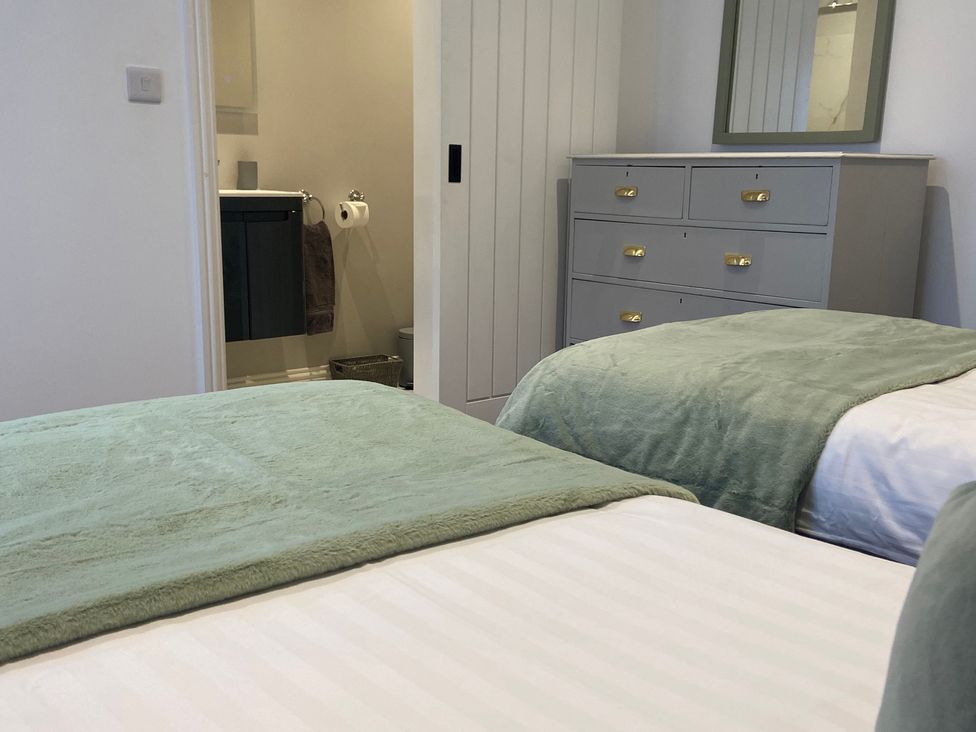 A bedroom with two beds and a dresser at The Cart Shed in Bedford