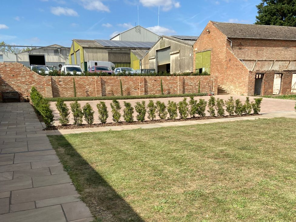 A garden with bushes and a paved area at The Cart Shed in Bedford
